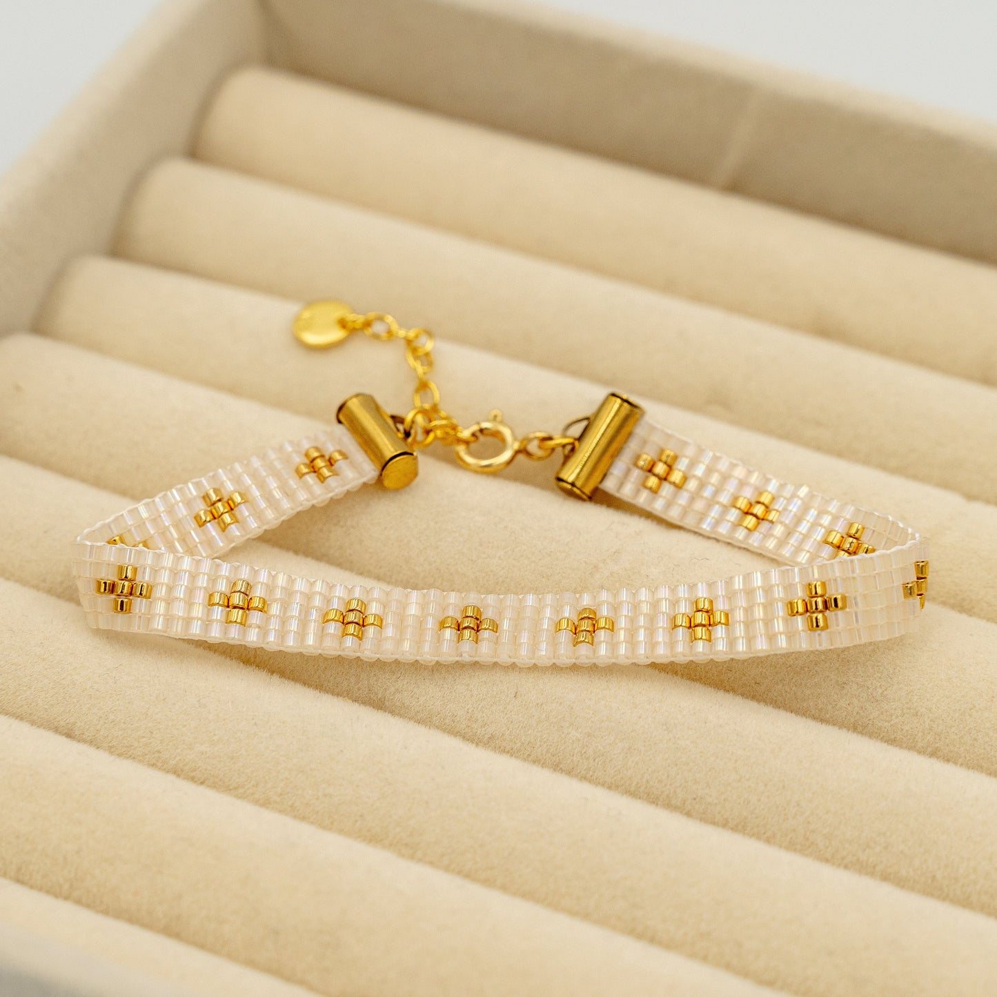 Håndsyet armbånd med forgyldte guldperler i changerende beige, forfra